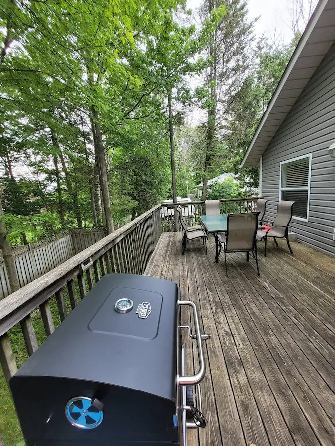 Large private deck with BBQ and outdoor dining surrounded by trees